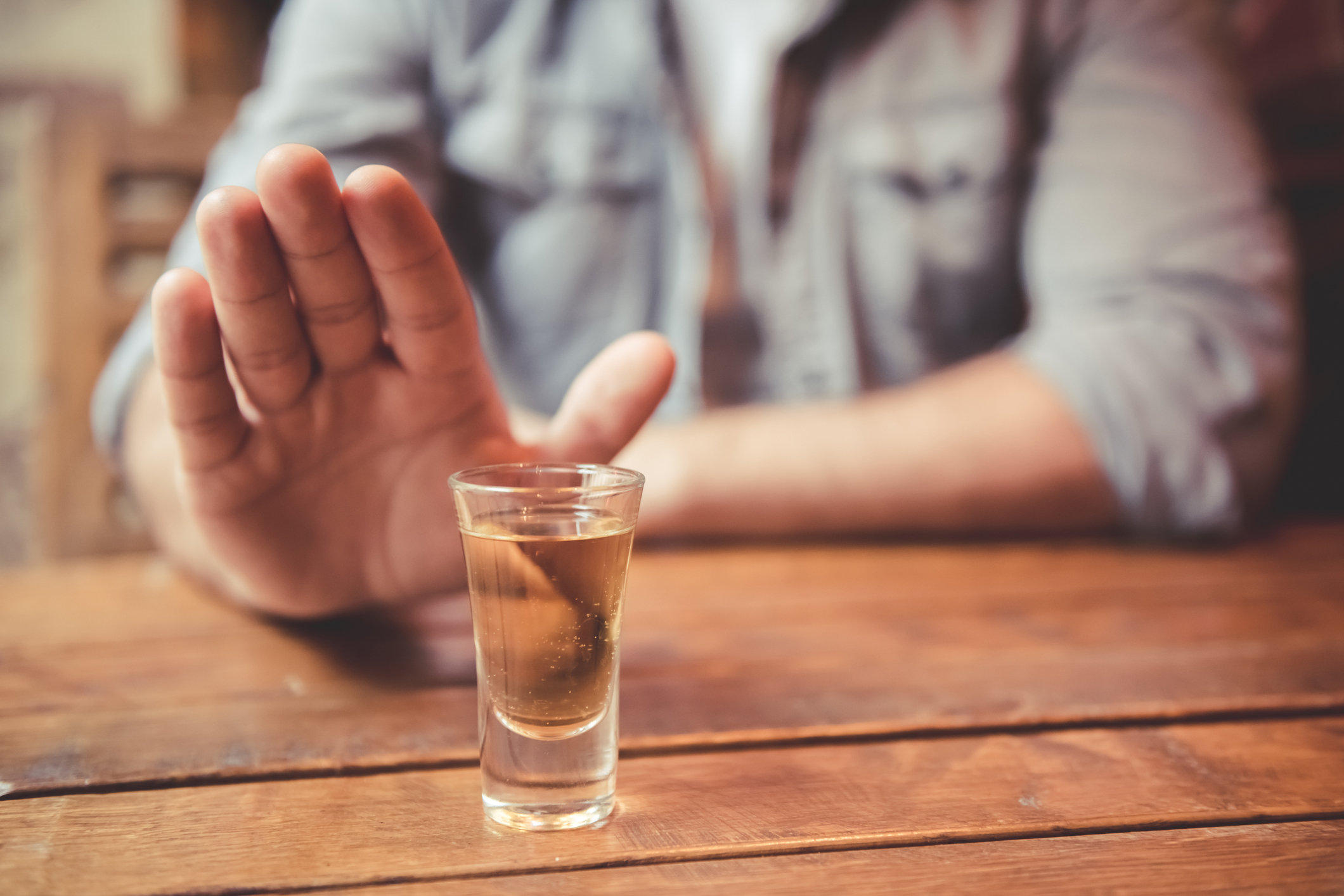 Cropped image of man showing stop gesture and refusing to drink